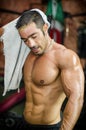 Muscular bodybuilder drying sweat from his face with a towel