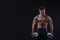 Muscular bodybuilder guy doing exercises with dumbbells over black background Royalty Free Stock Photo