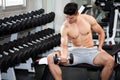 Muscular bodybuilder guy doing exercises sitting with weight lifting dumbbells in gym . Shirtless sport young fitness man training Royalty Free Stock Photo