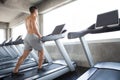 Muscular bodybuilder guy Exercise running on treadmill In the gym .sport young fitness man shirtless is working out training with Royalty Free Stock Photo