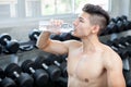 Muscular bodybuilder guy sitting on a bench drinking water after Royalty Free Stock Photo