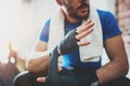 Muscular Boxer man prepairing hands for hard kickboxing training session in gym.Bearded Young athlete tying black boxing Royalty Free Stock Photo