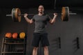 Brutal man holding heavyweight barbell on shoulders in gym Royalty Free Stock Photo