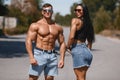 Muscular couple outdoors. Sporty man and woman showing muscles Royalty Free Stock Photo