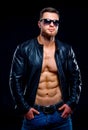 Muscular and fit young bodybuilder. Fitness male model posing over dark background. Leather jacket on naked torso. Royalty Free Stock Photo