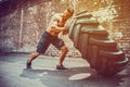 Muscular fitness shirtless man moving large tire in gym center, concept lifting, workout cross fit training Royalty Free Stock Photo