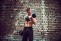 Muscular guy doing exercises with dumbbell against a brick wall Royalty Free Stock Photo