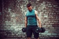 Muscular guy doing exercises with dumbbell against a brick wall Royalty Free Stock Photo