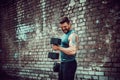 Muscular guy doing exercises with dumbbell against a brick wall Royalty Free Stock Photo