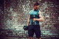 Muscular guy doing exercises with dumbbell against a brick wall Royalty Free Stock Photo