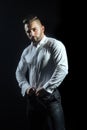 Muscular handsome guy on black background is posing wearing elegant white shirt and black trousers. Dress code for work Royalty Free Stock Photo