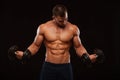 Muscular handsome man is training with dumbbells in gym. isolated on black background with copyspace Royalty Free Stock Photo