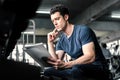 Muscular handsome trainer looking at fitness plan on clipboard for working out in the fitness gym