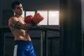 Muscular hardworking fighter practicing with punching bag indoor. Royalty Free Stock Photo