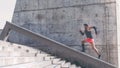 Muscular hispanic dark-skinned male athlete build running up a flight of stairs with speed.Concret background wall with