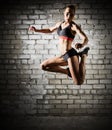 Muscular jumping woman on brick wall (dark version) Royalty Free Stock Photo