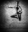 Muscular jumping woman on brick wall (monochrome version) Royalty Free Stock Photo