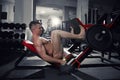 Muscular legs, handsome bodybuilder workout on trainer in the gym Royalty Free Stock Photo