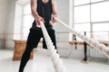 Muscular male athlete doing exercises with rope at crossfit gym