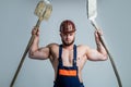 muscular man architect in engineer boilersuit and protective hard hat hold shovel, construction site Royalty Free Stock Photo