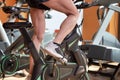 Muscular man biking in the gym, exercising legs doing cardio workout cycling bikes, spinning class.