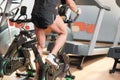 Muscular man biking in the gym, exercising legs doing cardio workout cycling bikes, spinning class.
