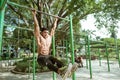 a muscular man without clothes doing L pull-up exercises using iron bar