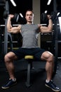 Muscular man doing dumbbell overhead press in the gym