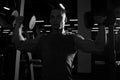 Muscular man doing dumbbell overhead press in the gym. Silhouette