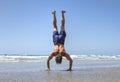 Muscular man doing handstand on beach Royalty Free Stock Photo