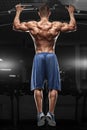 Muscular man doing pull up on horizontal bar in gym, working out. Strong fitness male pulling up, showing back Royalty Free Stock Photo