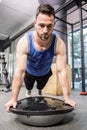 Muscular man doing push up on bosu ball