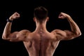 Muscular man flexing biceps, rear view isolated on black background. Body-building Royalty Free Stock Photo