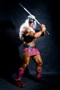 Muscular man in an image of a barbarian with a raised sword. Royalty Free Stock Photo