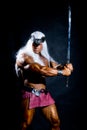 Muscular man in an image of a barbarian with a raised sword. Royalty Free Stock Photo