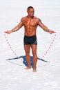 Muscular man with jump rope on the beach
