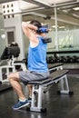 Muscular man lifting dumbbell while sitting on bench Royalty Free Stock Photo