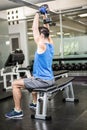 Muscular man lifting dumbbell while sitting on bench Royalty Free Stock Photo