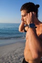 Muscular man listening to music on headphones at beach Royalty Free Stock Photo