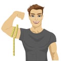 Muscular man measuring biceps with tape measure