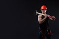 Muscular man in orange helmet with great anatomy posing on a black background with a big hummer in his hands. Royalty Free Stock Photo