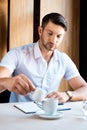 Muscular man pouring cream in coffee in cafe Royalty Free Stock Photo