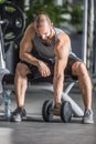 Muscular man practicing with dumbbells in fitness gym
