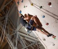 Muscular man practicing rock-climbing on a rock wall indoors Royalty Free Stock Photo