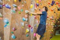 Muscular man practicing rock-climbing on a rock wall indoors Royalty Free Stock Photo