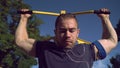 A muscular man is pulling himself up in the park.