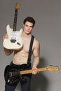 Muscular man shirtless holding two electric guitars