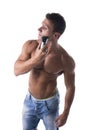 Muscular man shirtless using electric shaver, looking away Royalty Free Stock Photo