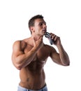 Muscular man shirtless using electric shaver, looking to a side Royalty Free Stock Photo