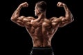 Muscular man showing back muscles, isolated on black background. Strong male rear view